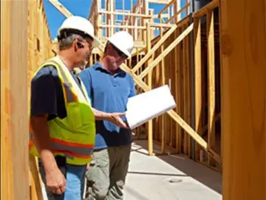 Two men in hard hats looking at a building plan.
