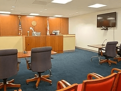 A courtroom with chairs, tables and a television.
